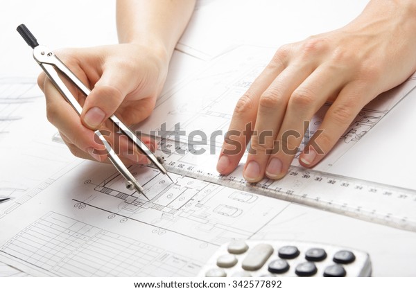 Architect working\
on blueprint. Architects workplace - architectural project, plan,\
drawing, sketch, ruler, calculator and divider compass.\
Construction concept. Engineering\
tools