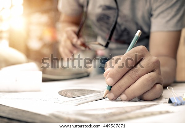 Architect working\
on blueprint. Architects workplace - architectural project, plan,\
drawing, sketch, ruler, calculator and divider compass.\
Construction concept.Architects\
working