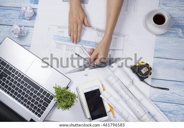 Architect working on blueprint. Architects
workplace - architectural project, blueprints, ruler, calculator,
laptop and divider compass. Construction concept. Engineering
tools. Top view.
