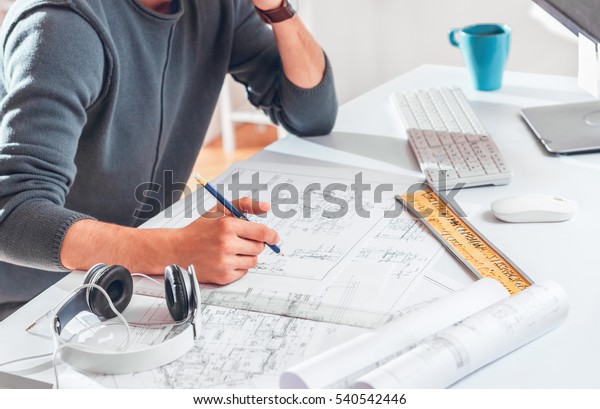 Architect working on\
blueprint. Architects workplace - architectural project,\
blueprints, ruler, laptop and divider compass. Construction\
concept. Engineering\
tools.