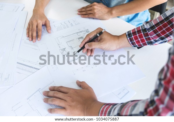 Architect working on blueprint,\
Engineer meeting working with partner colleagues and engineering\
tools for architectural project, Construction\
concept.