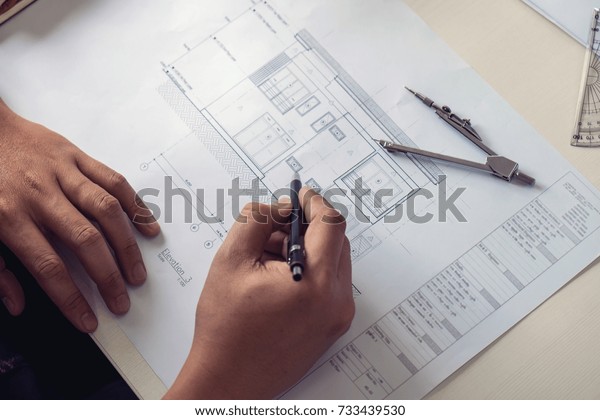 Architect\
working on blueprint, Engineer working with engineering tools for\
architectural project on workplace, Construction concept - building\
project, blueprints, ruler and\
dividers.
