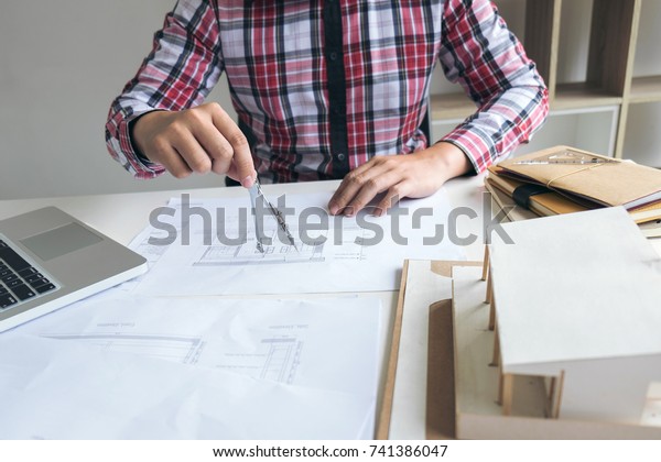Architect working on\
blueprint, Engineer working with engineering tools for\
architectural project on\
workplace.
