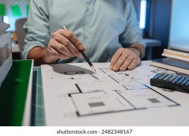 The architect is working on blueprint of important project by using his creativity, the engineer drafts and uses construction design equipment, full of design paperwork on the architect's desk - Powered by Shutterstock