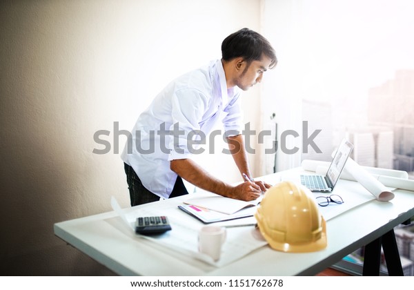 Architect working on\
blueprint.engineer inspective in workplace - architectural project,\
blueprints,ruler,calculator,laptop and divider compass. working\
concept.