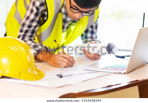 Architect working on blueprint.engineer inspective in\
workplace - architectural project,\
blueprints,ruler,calculator,laptop and divider compass.\
Construction concept, selective focus\
