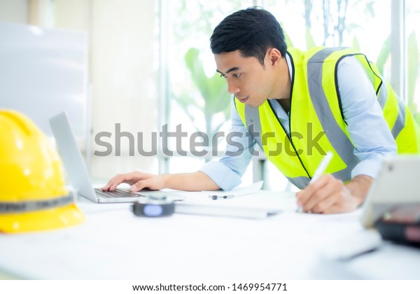 Architect working on blueprint.engineer inspective in\
workplace - architectural project,\
blueprints,ruler,calculator,laptop and divider compass.\
Construction concept. Engineering tools,\

