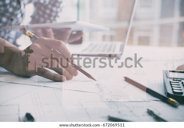 architect working on\
real estate project with digital tablet and living house blueprint\
at office. Business, people, construction and building concept\
double exposure with\
crane