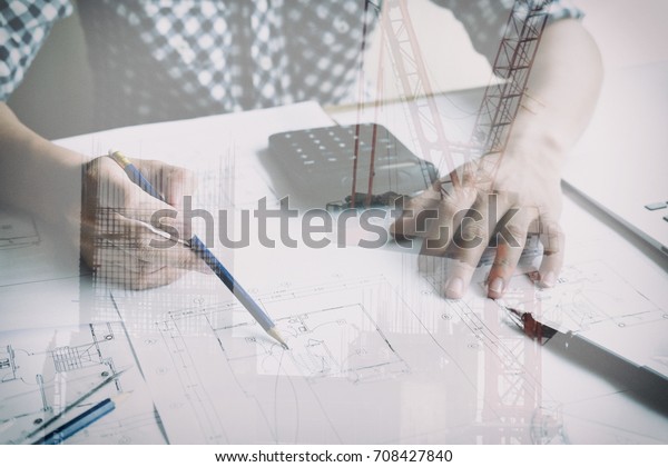 architect working on real estate project at\
workplace. Male engineer hand working with living house blueprint\
at office. Business, people, construction and building concept\
double exposure with\
crane