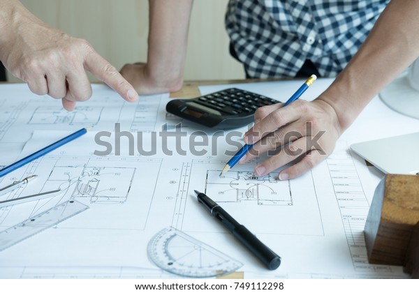architect working on real estate project with partner at\
workplace. Male engineer hand discussing with colleague on living\
house blueprint at office. Business, people, construction and\
building 