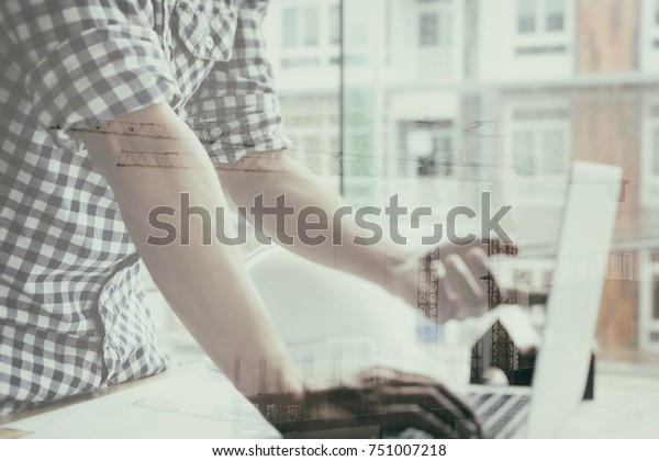  architect working on real estate project at
workplace. Male engineer hand working with laptop computer and
living house blueprint at office. Business, people, construction
and building concept