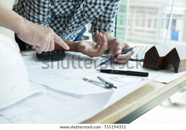  architect working on real estate project with\
partner at workplace. Male engineer hand discussing with colleague\
on living house blueprint at office. Business, people, construction\
and building conce