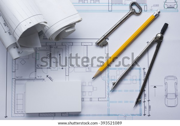 Architect worplace top view. Architectural project,\
blueprints, blueprint rolls and  divider compass, key, blank\
business card on plans. Construction background. Engineering tools.\
Copy space