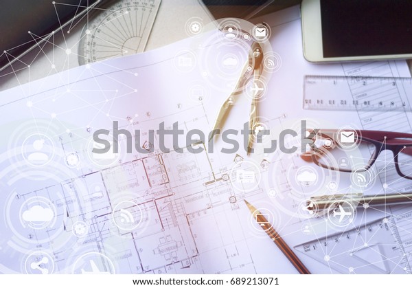 The architects \'and engineers\' desks are full of\
working equipment such as blueprints, pens, pencil, glasses, mobile\
phones with icon diagram.