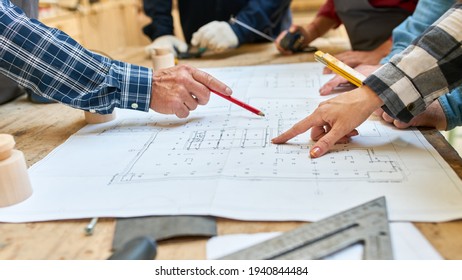 Architects and craftsmen discuss an architectural drawing in a meeting