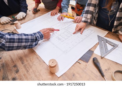 Architects and craftsmen look at a floor plan for a house building project