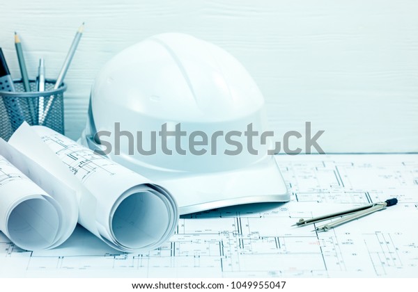 architects drawing tools and instruments,\
helmet, blueprint rolls on engineering project drawing.\
construction concept\
background.