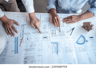 Architects or engineering team consulting and analyzing working on objects tools and construction drawings inspection planning new architectural project on blueprint and model house in modern office. - Powered by Shutterstock