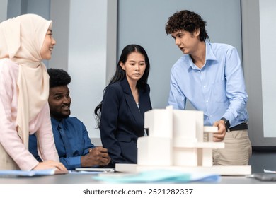 Architects engineers collaborating on building design project in modern office, diverse team of professionals female muslim architect and male engineers discussing architectural model of structure - Powered by Shutterstock