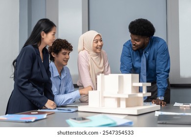 Architects engineers collaborating on building design project in modern office, diverse team of professionals female muslim architect and male engineers discussing architectural model of structure - Powered by Shutterstock