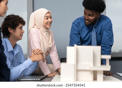 Architects engineers collaborating on building design project in modern office, diverse team of professionals female muslim architect and male engineers discussing architectural model of structure - Powered by Shutterstock