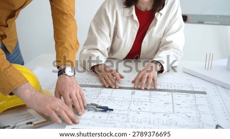 Architects and engineers collaborating on a building project, reviewing blueprints and technical drawings, planning future construction development with focus on design details
