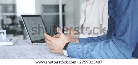 Architects and engineers collaborating on a technical blueprint, discussing construction plans and urban planning details during an office meeting with a laptop displaying cad drawings