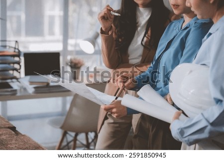 Architects and engineers engaged in a collaborative discussion, pointing at blueprints while strategizing design and construction plans in the office environment