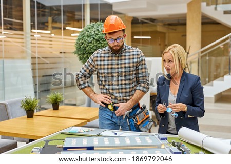 architects and engineers working with blueprints and architectural plan, female director talk with engineer, discuss building design,Home or house town planning