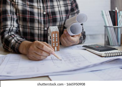 Architect's Hand Sitting On The Work Table To Design And Draw A Picture Of The House