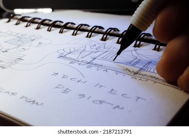 Architect's hands are sketching architectural plans with pencils on a sketchbook on a desk with a laptop. - Shutterstock ID 2187213791