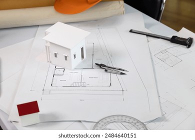 Architects house model with measurement tool and blueprints on architect desk. A architects home model with plan and blueprints. Business, architecture, building and construction concept. - Powered by Shutterstock