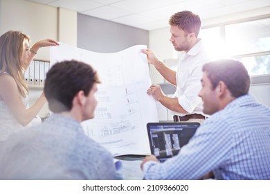 Architects Reviewing Blueprints In Meeting In Office