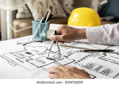 Architects use compasses to write on the blueprints of the houses, designing the buildings according to the standards and the law, designing the houses according to the needs of the residents. - Shutterstock ID 2034702059