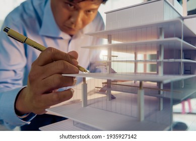 Architects worked thinking design architecture with building model, Design from his idea stationery on desk office. Startup and analysis of the architecture of building structure.