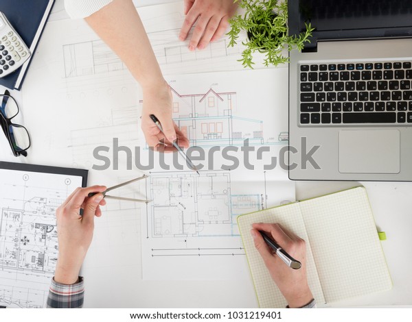 Architects working on blueprint,\
real estate project. Architect workplace - architectural\
project