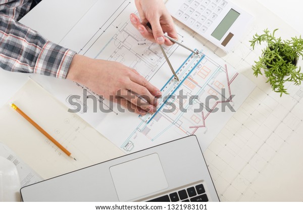 Architects working on blueprint, real estate
project. Architect workplace - architectural project, blueprints,
ruler, calculator, laptop and divider compass. Construction
concept. Engineering
tools.