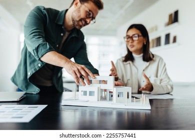 Architects working on a house model in a creative office. Two young business people having a discussion on a new design project. - Powered by Shutterstock