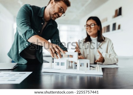 Architects working on a house model in a creative office. Two young business people having a discussion on a new design project.