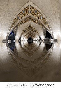 Architectural archway with Islamic geometric patterns, reflection on wet floor, symmetrical design, interior view, religious architecture, cultural heritage, travel, tourism, artistic