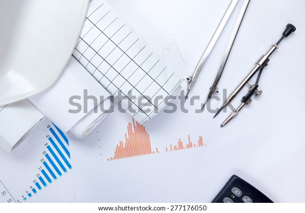 Architectural blueprints,\
blueprint rolls, compass divider, calculator, white safety on\
growth chart. Engineering tools view from the top. Copy space.\
Construction\
background