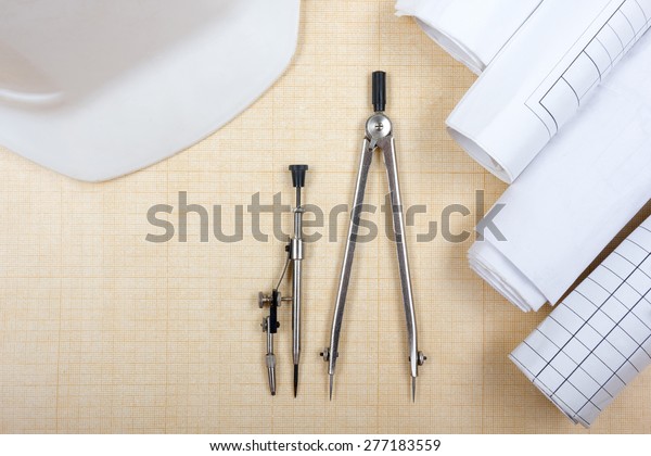 Architectural blueprints,\
blueprint rolls, compass divider, white safety on graph paper.\
Engineering tools view from the top. Copy space. Construction\
background