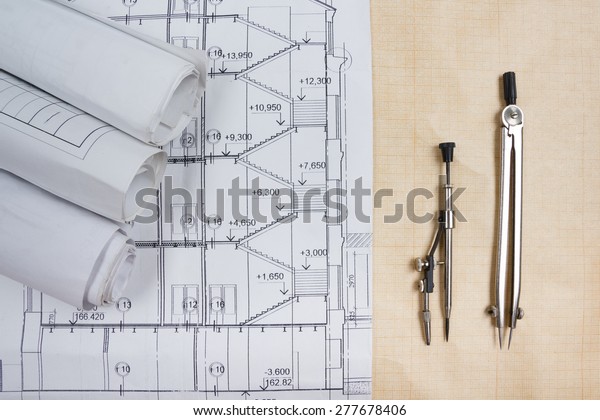 Architectural blueprints, blueprint rolls,\
compass divider on graph paper. Engineering tools view from the\
top. Copy space. Construction\
background