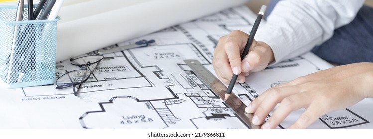 Architectural building design and construction plans with blueprints, Young man was designing a building or architecture with a ruler, pen, pencil, tape measure, architect hat and other equipment. - Shutterstock ID 2179366811