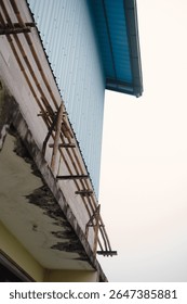 An architectural composition captures a unique facade, featuring weathered textures, unconventional wooden support structures, and a stark minimalist design against a soft sky, emphasizing angles