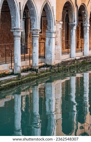Architectural detail with the arch columns reflecting in the water canals of Venice, Italy.