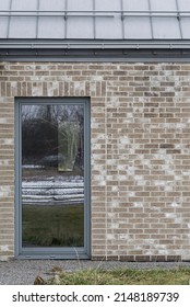 Architectural Detail For Building, Single Family House. Roof Made Of Aluminum Sheet In Gray Color. Walls Made Of Brick And Window Woodwork In Grey Color. British Style Of The Building.