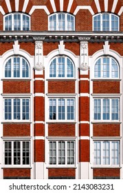 Architectural Detail Of Victorian Building, With Red Brick, Arched Windows And Decorative Plaster Work In Art Nouveau Style. Geometric Background Image.