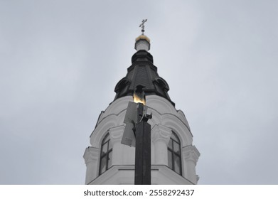 Architectural details of a religious building featuring a spire and cross against a cloudy sky - Powered by Shutterstock