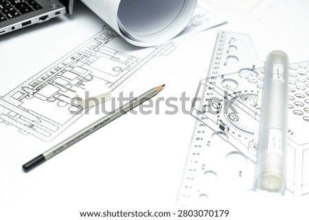 Architectural or electrical schematic diagram blueprint on a table with professional drafting tools, plastic rulers, an eraser, and a graphite pencil